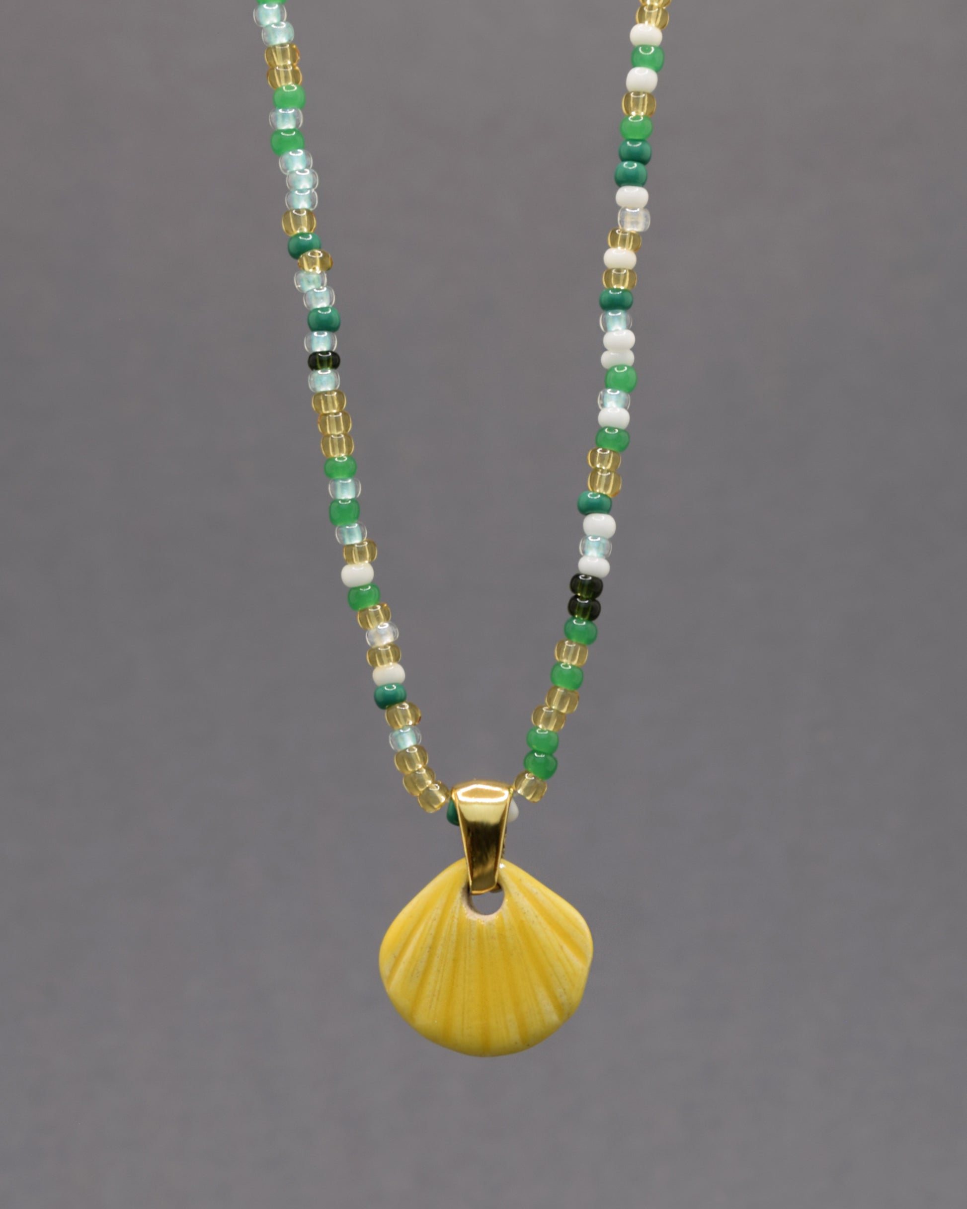 Colar com pendente de concha pintada em amarelo. Peça artesanal em cerâmica que celebra o verão com cor e elegância.