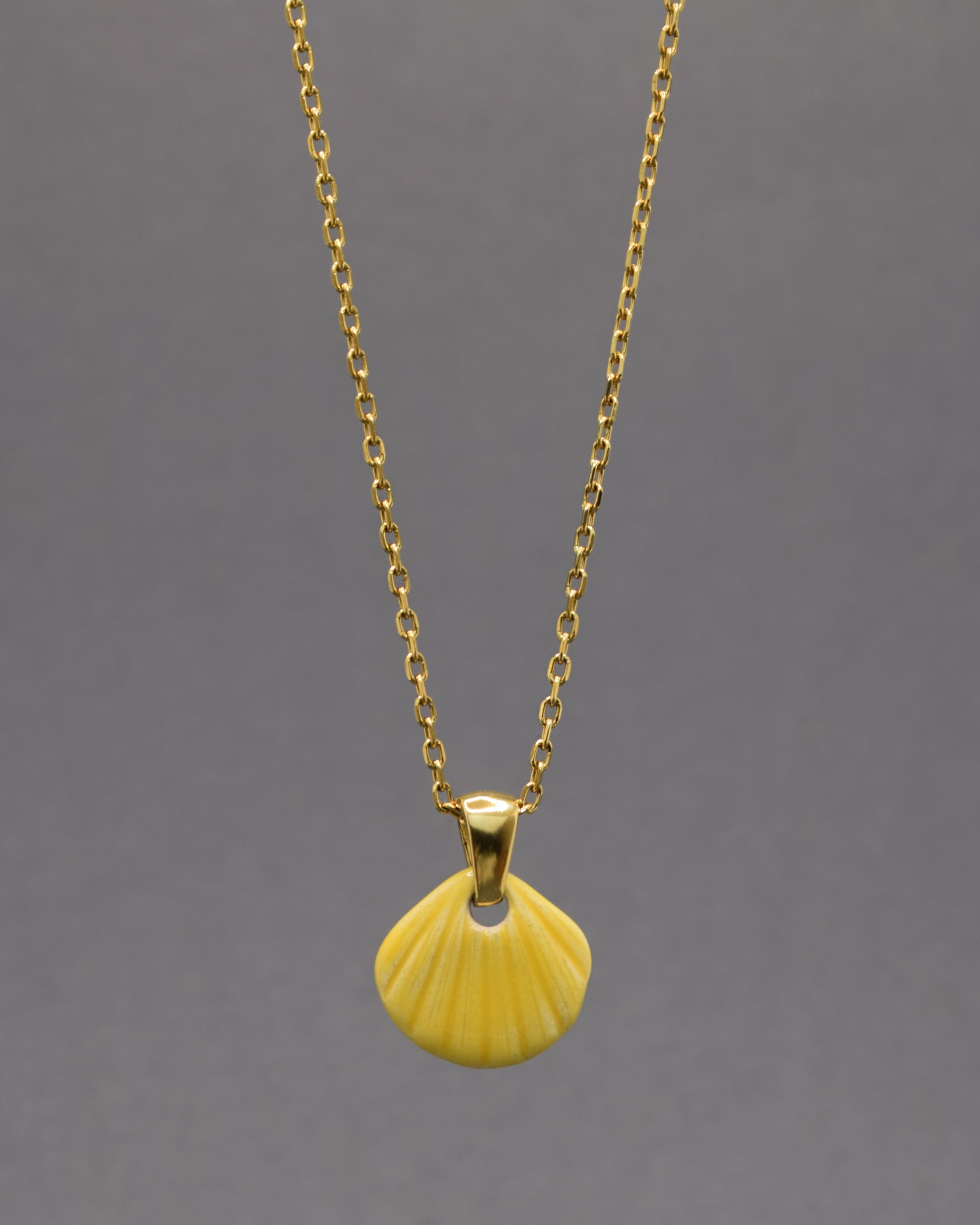 Colar com pendente de concha pintada em amarelo. Peça artesanal em cerâmica que celebra o verão com cor e elegância.