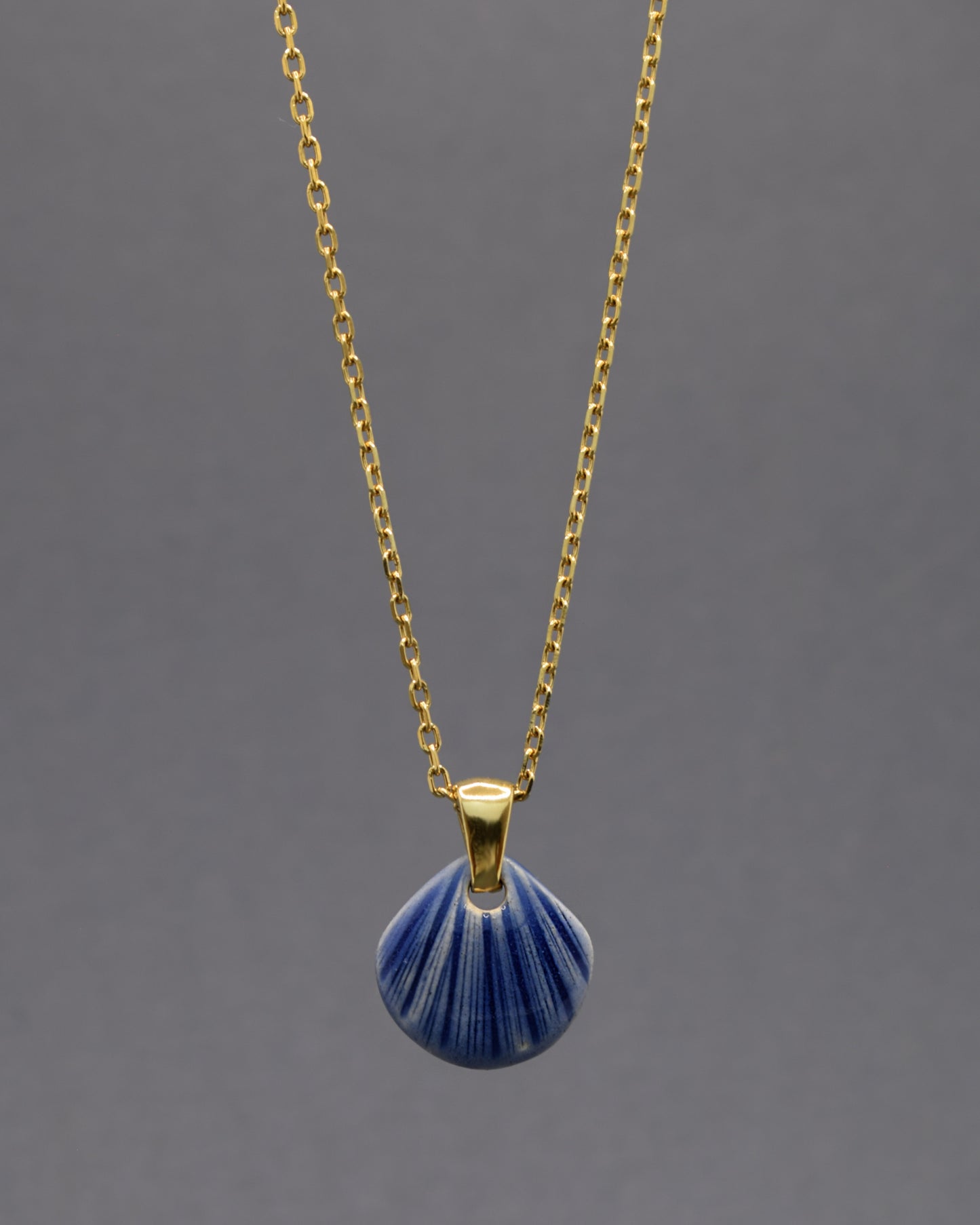 Colar artesanal com pendente de concha em cerâmica azul escuro, inspirado no mar e na serenidade. Elegante e versátil para qualquer ocasião.