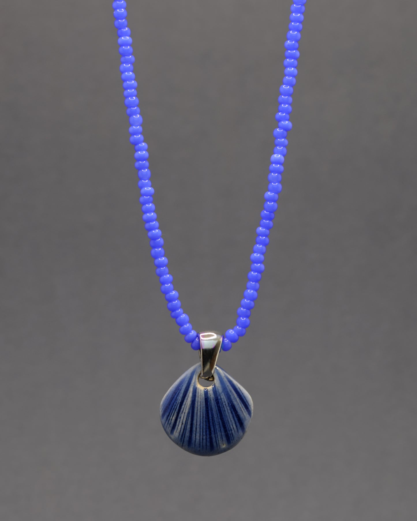 Colar artesanal com pendente de concha em cerâmica azul escuro, inspirado no mar e na serenidade. Elegante e versátil para qualquer ocasião.