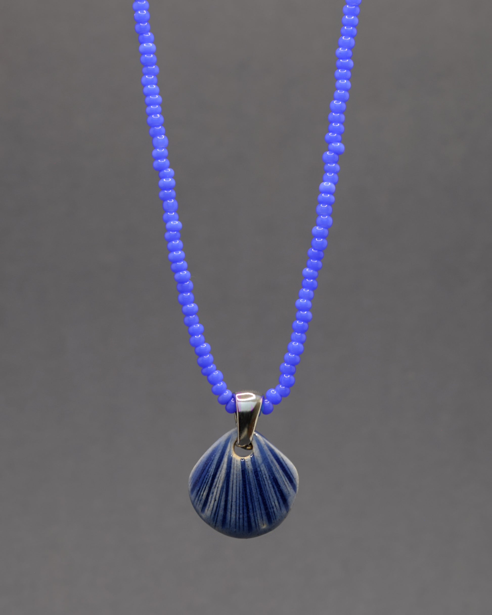 Colar artesanal com pendente de concha em cerâmica azul escuro, inspirado no mar e na serenidade. Elegante e versátil para qualquer ocasião.