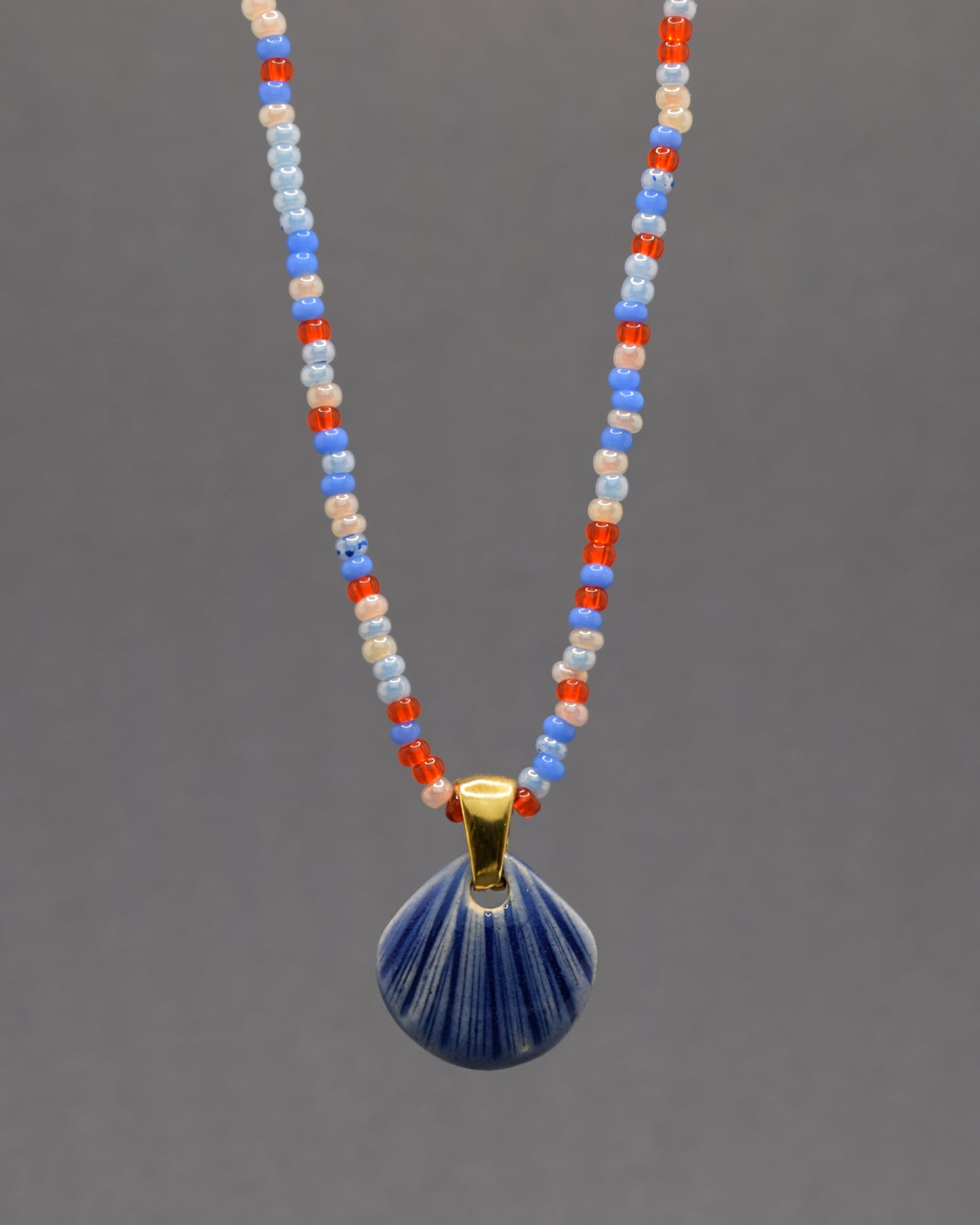 Colar artesanal com pendente de concha em cerâmica azul escuro, inspirado no mar e na serenidade. Elegante e versátil para qualquer ocasião.