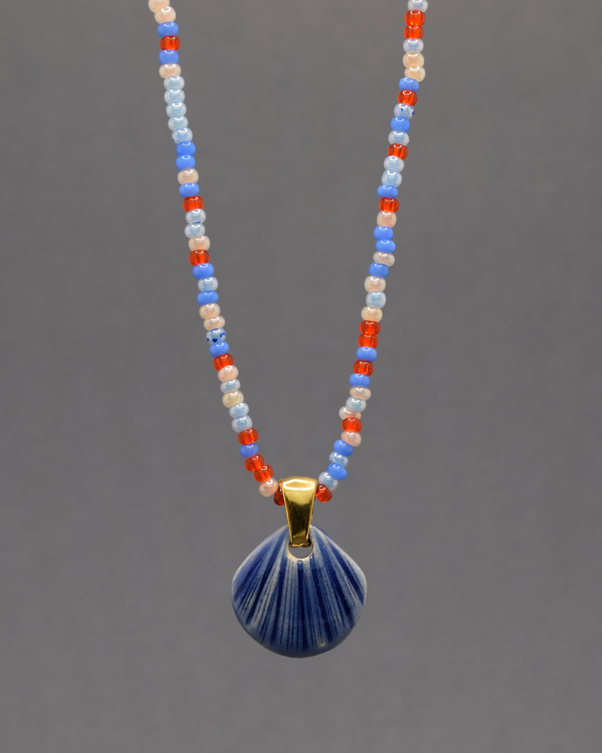 Colar artesanal com pendente de concha em cerâmica azul escuro, inspirado no mar e na serenidade. Elegante e versátil para qualquer ocasião.