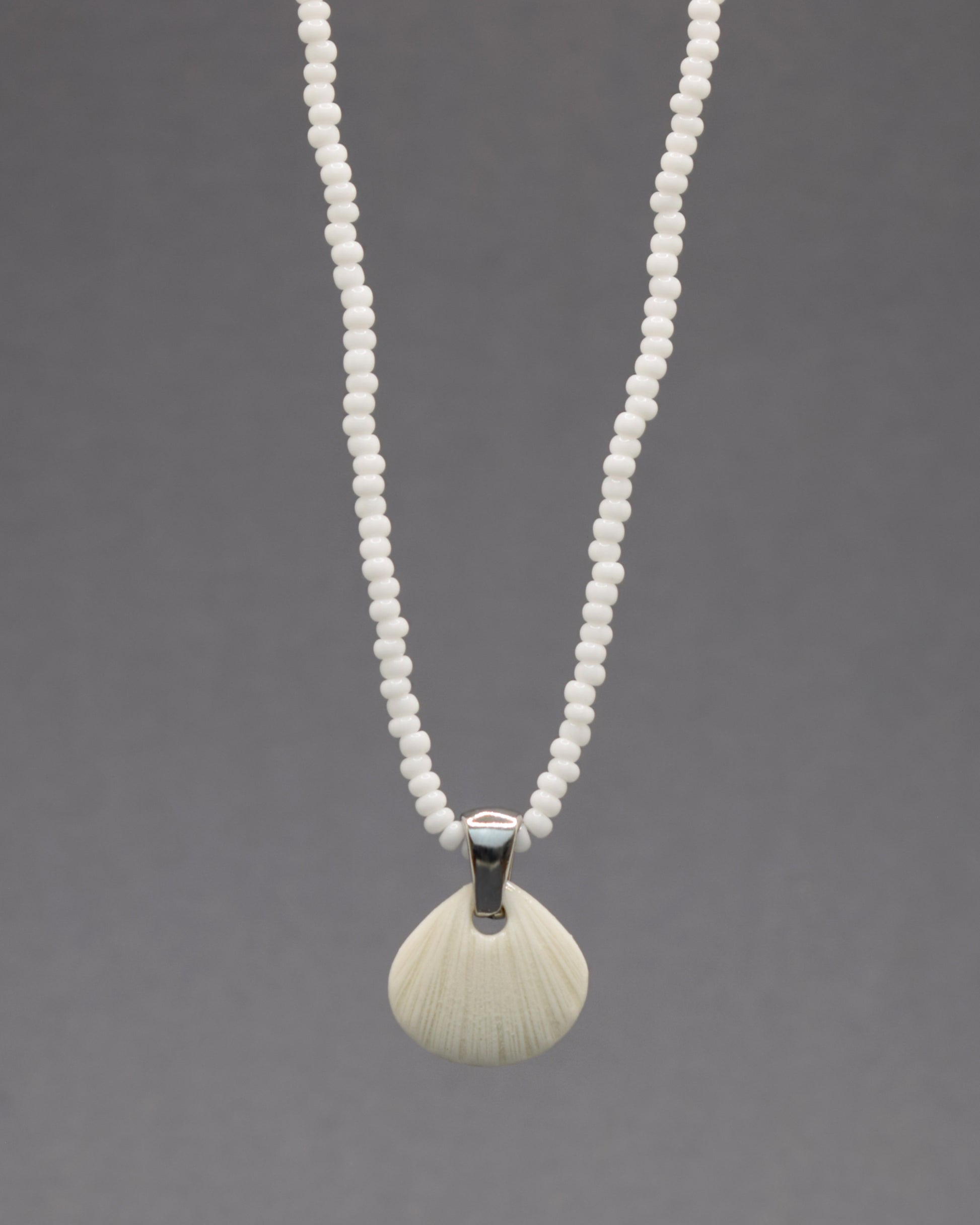 Colar com pendente de porcelana em forma de concha. Peça delicada, feita à mão, ideal para amantes do mar e do design artesanal.