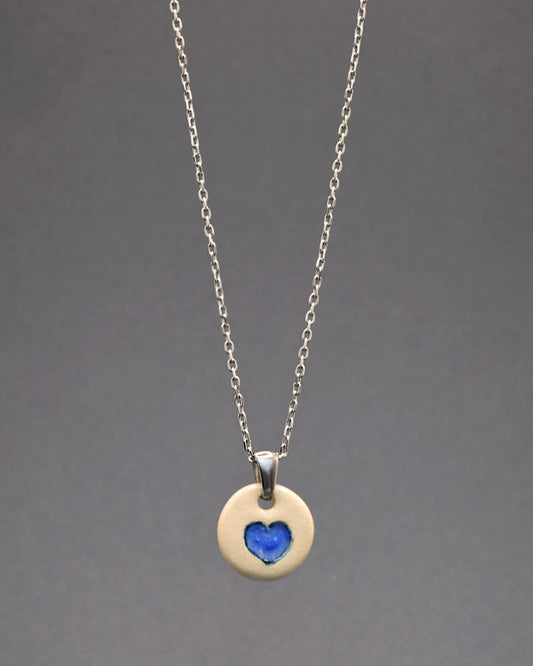 Este colar combina a durabilidade do aço inoxidável com a delicadeza da cerâmica. O seu pendente artesanal, um coração azul pintado à mão, evoca serenidade e amor. Uma fusão encantadora de resistência e sutileza, perfeita para expressar beleza e emoção