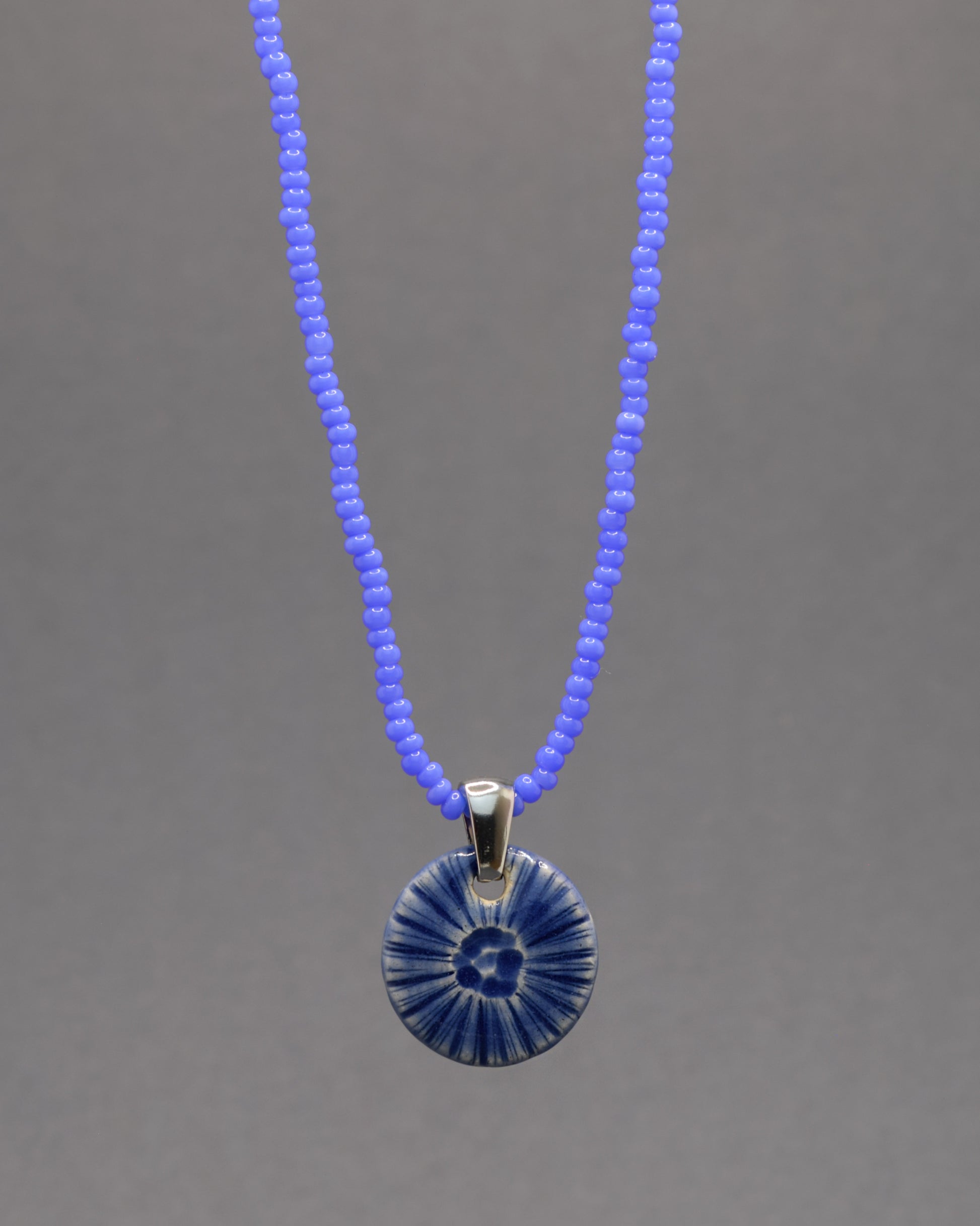 Colar artesanal em cerâmica azul escuro, inspirado na força do mar. Elegância contemporânea com acabamento único e orgânico.