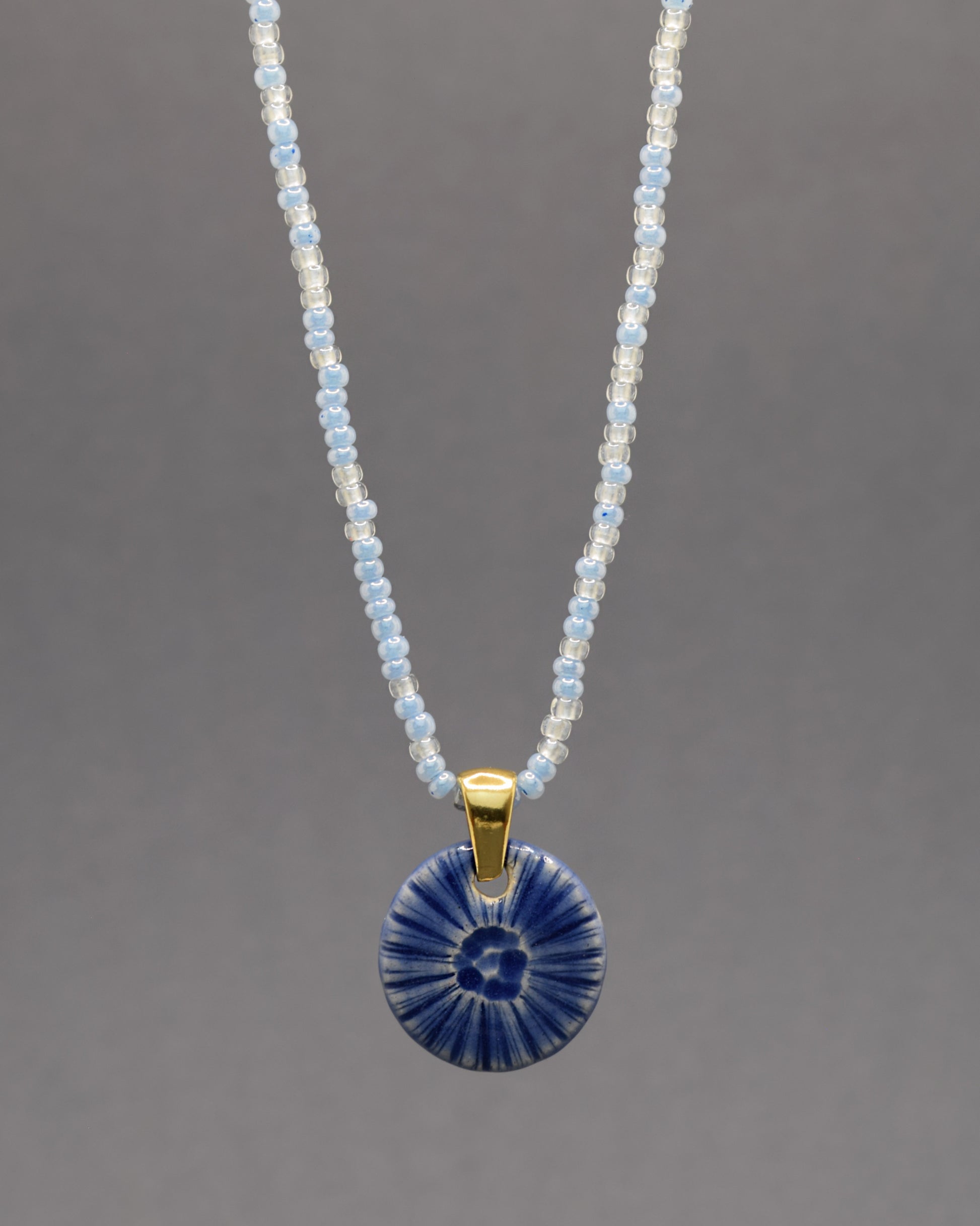 Colar artesanal em cerâmica azul escuro, inspirado na força do mar. Elegância contemporânea com acabamento único e orgânico.