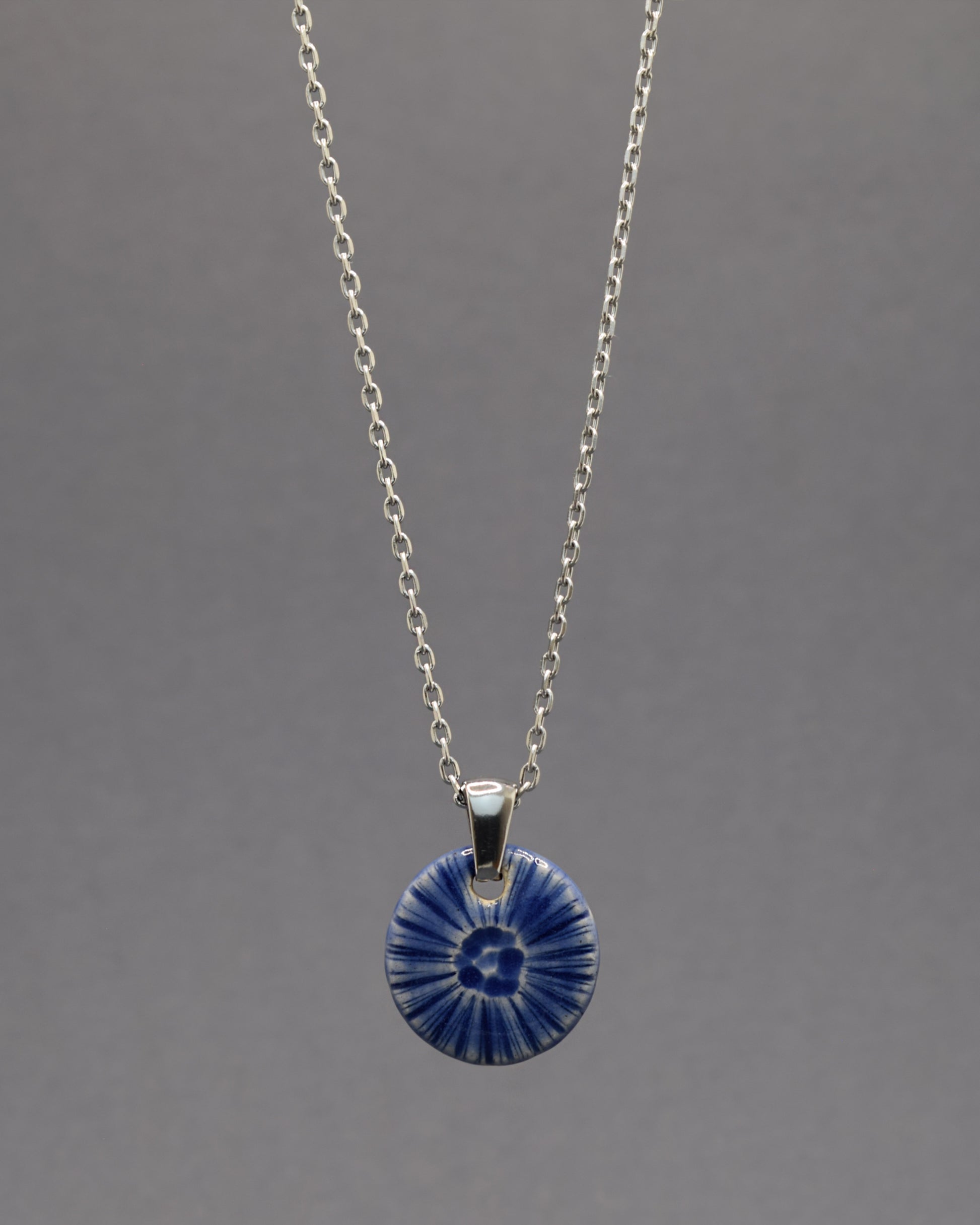 Colar artesanal em cerâmica azul escuro, inspirado na força do mar. Elegância contemporânea com acabamento único e orgânico.
