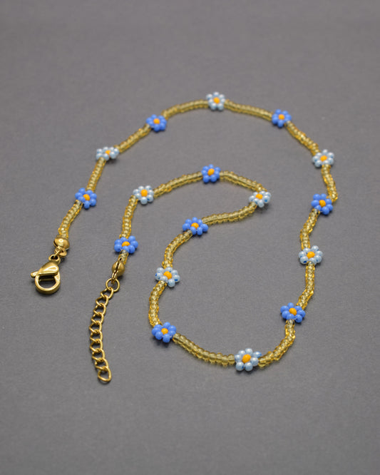 Colar com flores azul-claras e néon e missangas douradas semitransparentes, vibrante e delicado, perfeito para iluminar o teu estilo.