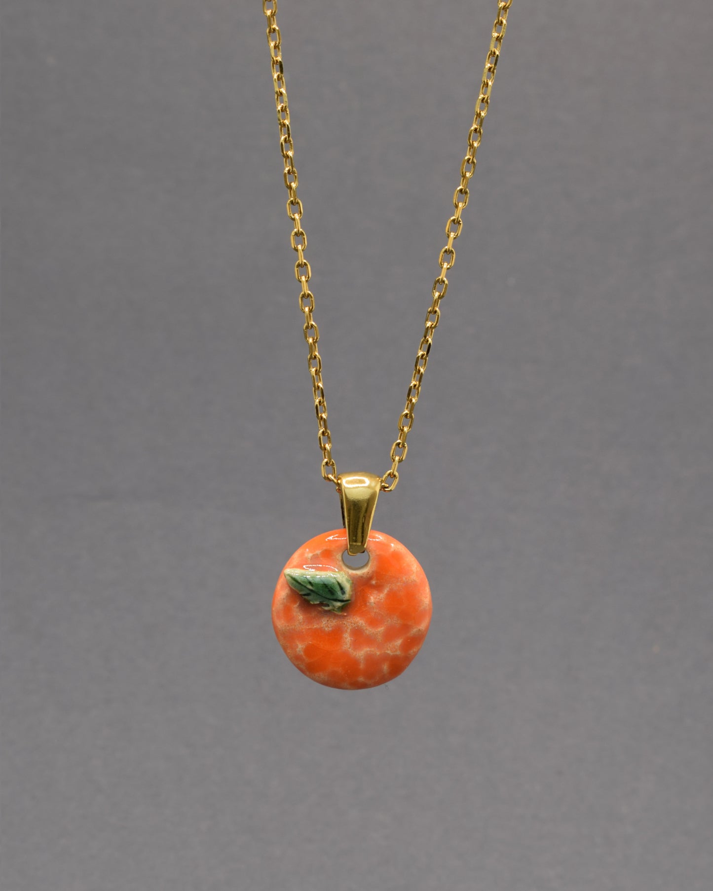 Colar com laranja e folha em cerâmica pintada à mão. Um apontamento de cor inspirado nos pomares portugueses, perfeito para dar vida a qualquer look.