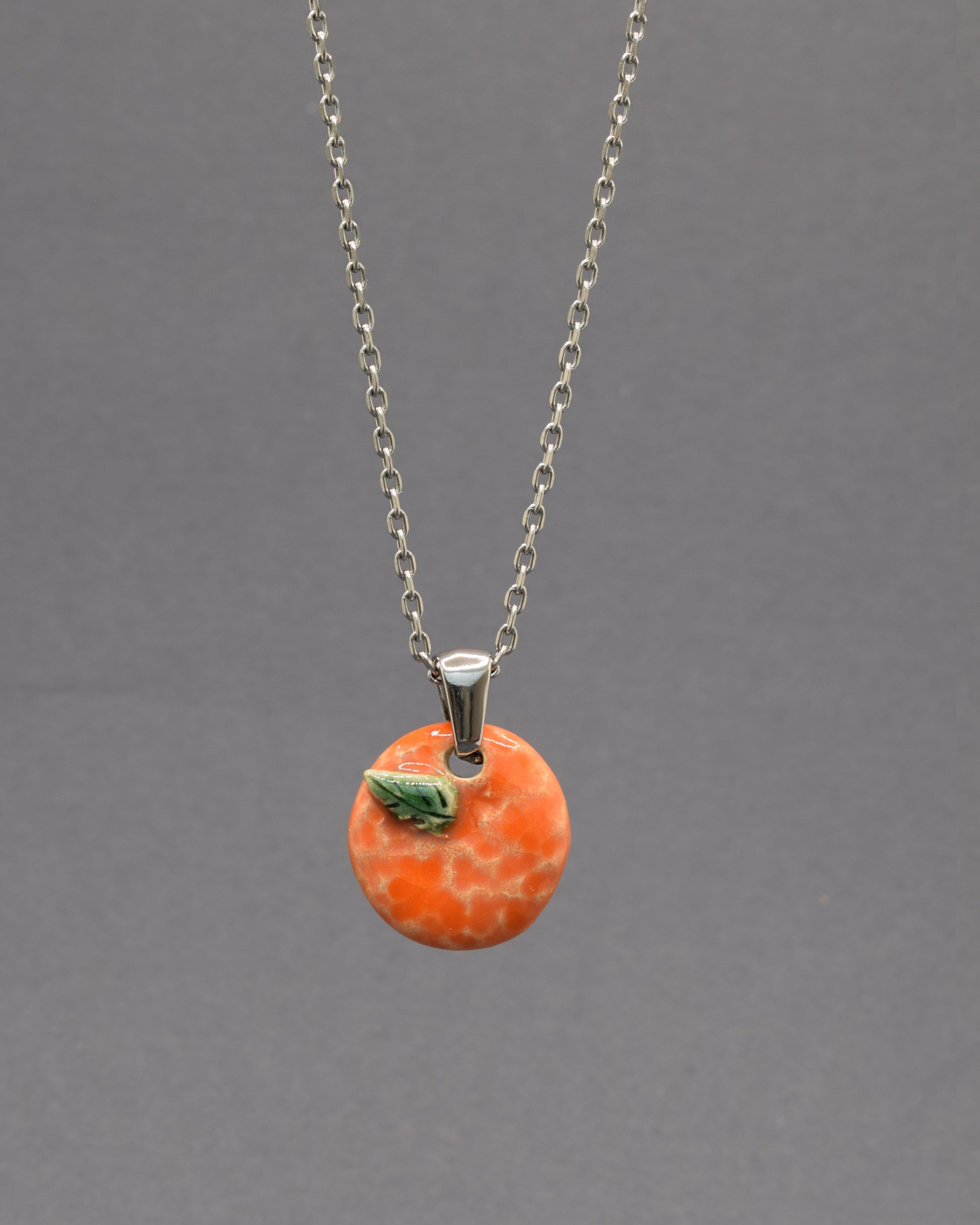 Colar com laranja e folha em cerâmica pintada à mão. Um apontamento de cor inspirado nos pomares portugueses, perfeito para dar vida a qualquer look.