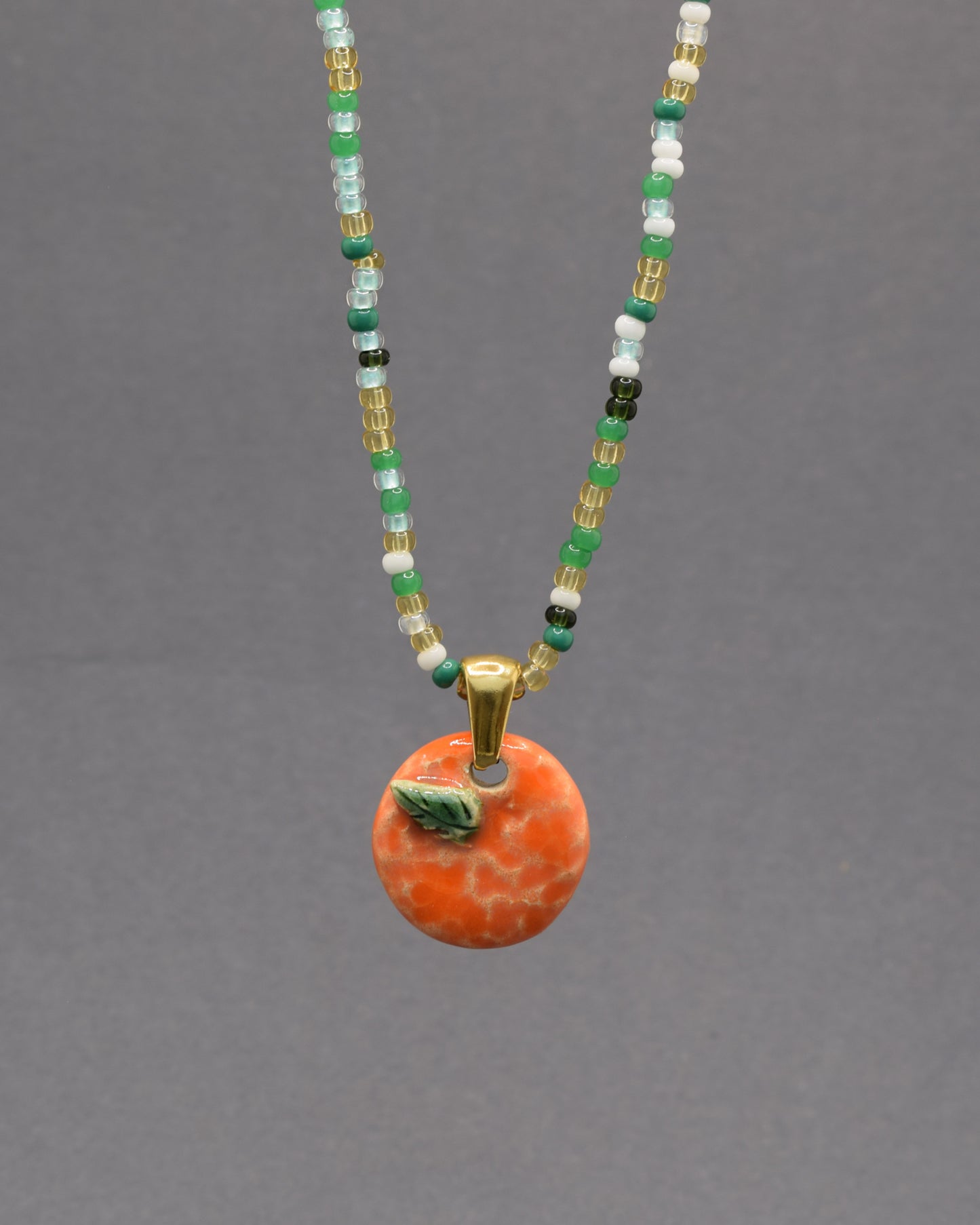Colar com laranja e folha em cerâmica pintada à mão. Um apontamento de cor inspirado nos pomares portugueses, perfeito para dar vida a qualquer look.