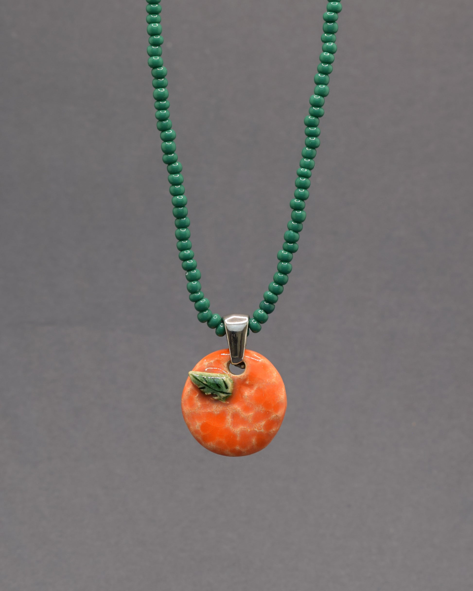 Colar com laranja e folha em cerâmica pintada à mão. Um apontamento de cor inspirado nos pomares portugueses, perfeito para dar vida a qualquer look.