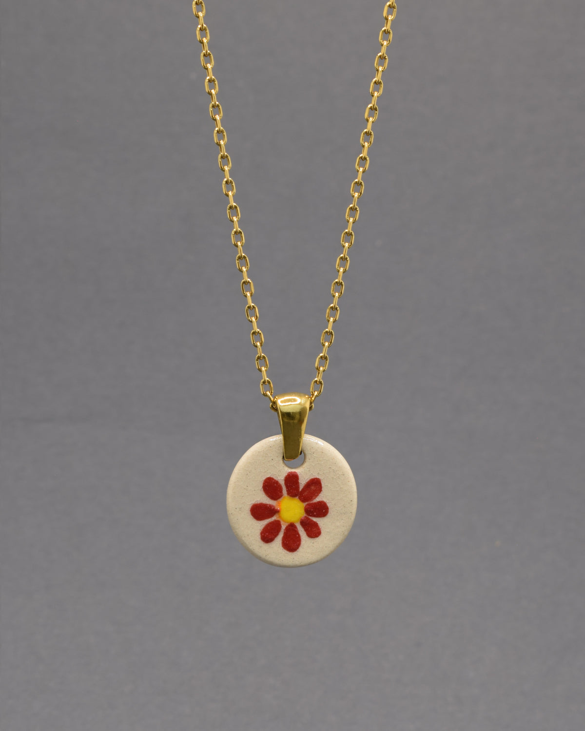 Colar Margarida Vermelha com pendente em cerâmica artesanal. Design vibrante e cheio de energia, perfeito para o seu estilo.