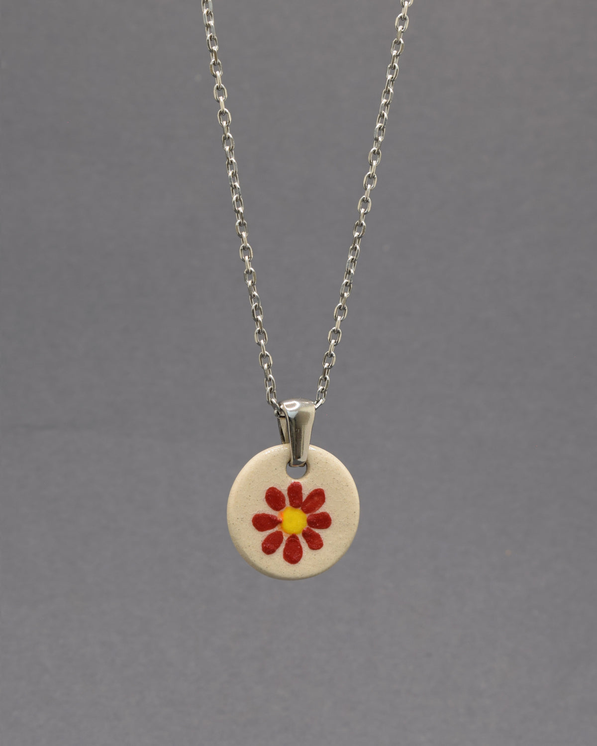 Colar Margarida Vermelha com pendente em cerâmica artesanal. Design vibrante e cheio de energia, perfeito para o seu estilo.