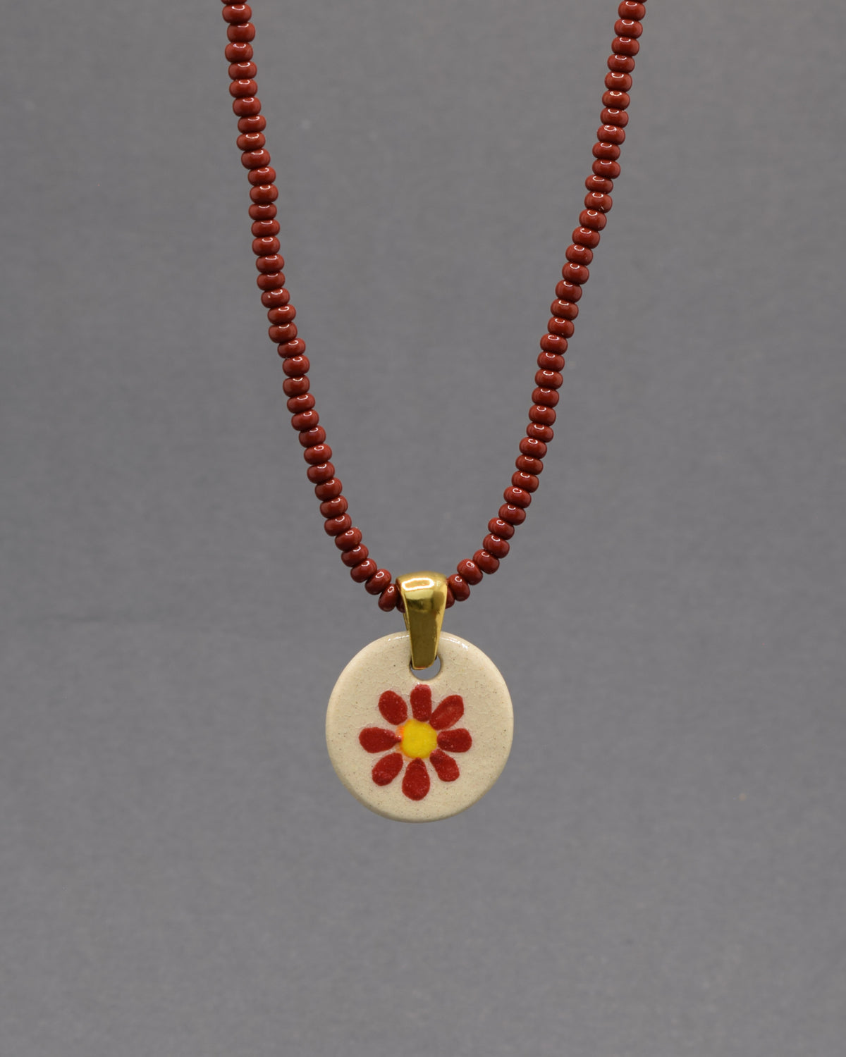 Colar Margarida Vermelha com pendente em cerâmica artesanal. Design vibrante e cheio de energia, perfeito para o seu estilo.