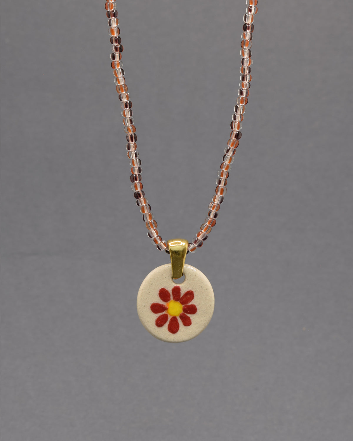 Colar Margarida Vermelha com pendente em cerâmica artesanal. Design vibrante e cheio de energia, perfeito para o seu estilo.