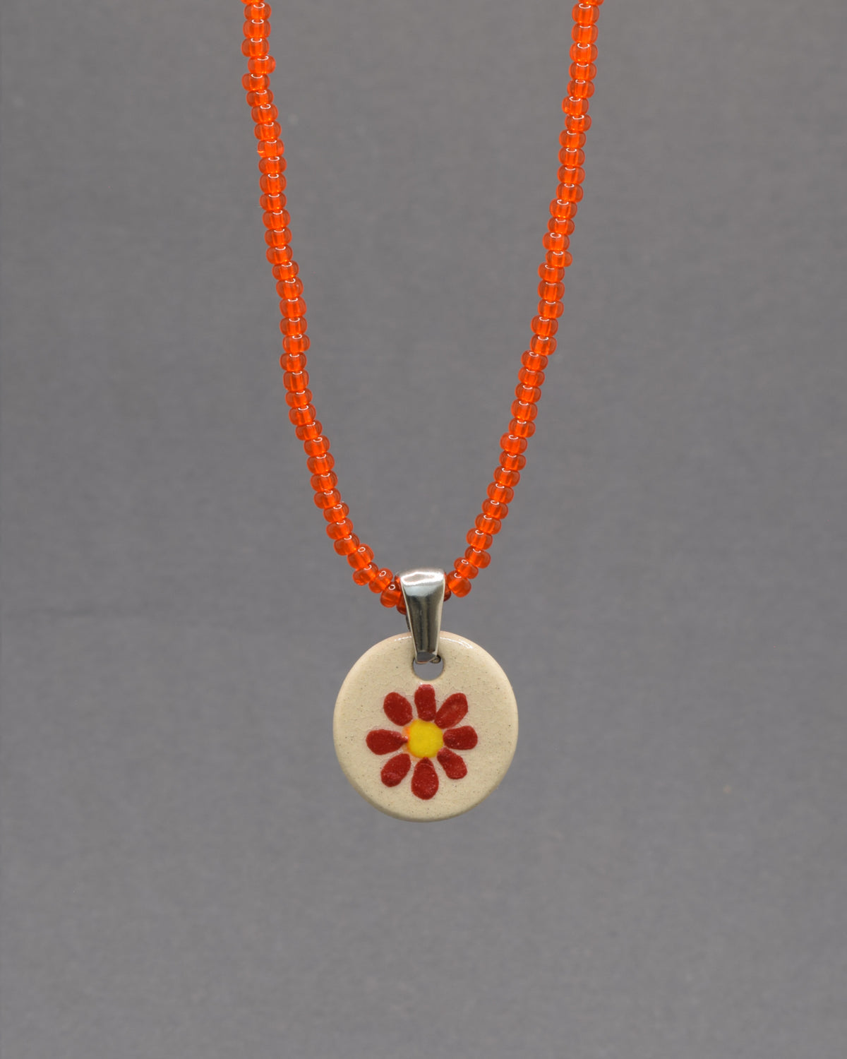 Colar Margarida Vermelha com pendente em cerâmica artesanal. Design vibrante e cheio de energia, perfeito para o seu estilo.
