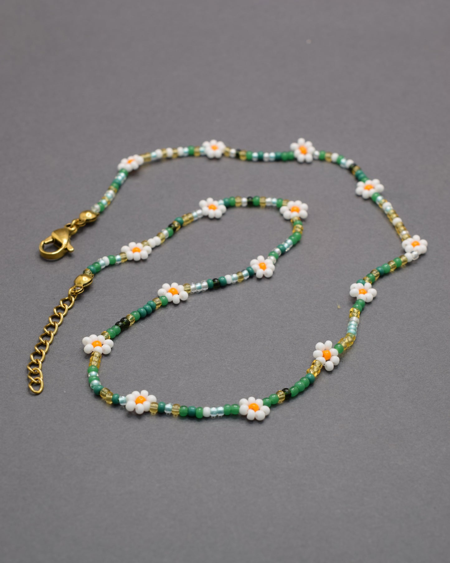 Colar com flores brancas e missangas mix em tons verdes, delicado e harmonioso, perfeito para um look fresco e natural.