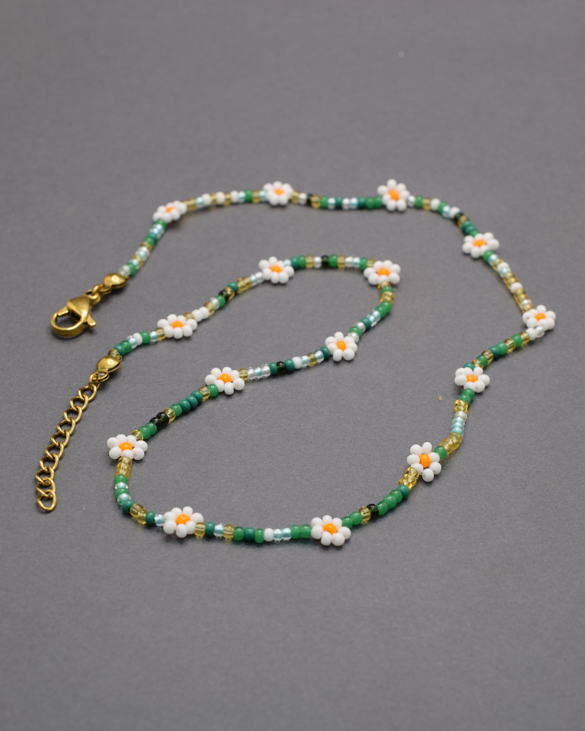 Colar com flores brancas e missangas mix em tons verdes, delicado e harmonioso, perfeito para um look fresco e natural.