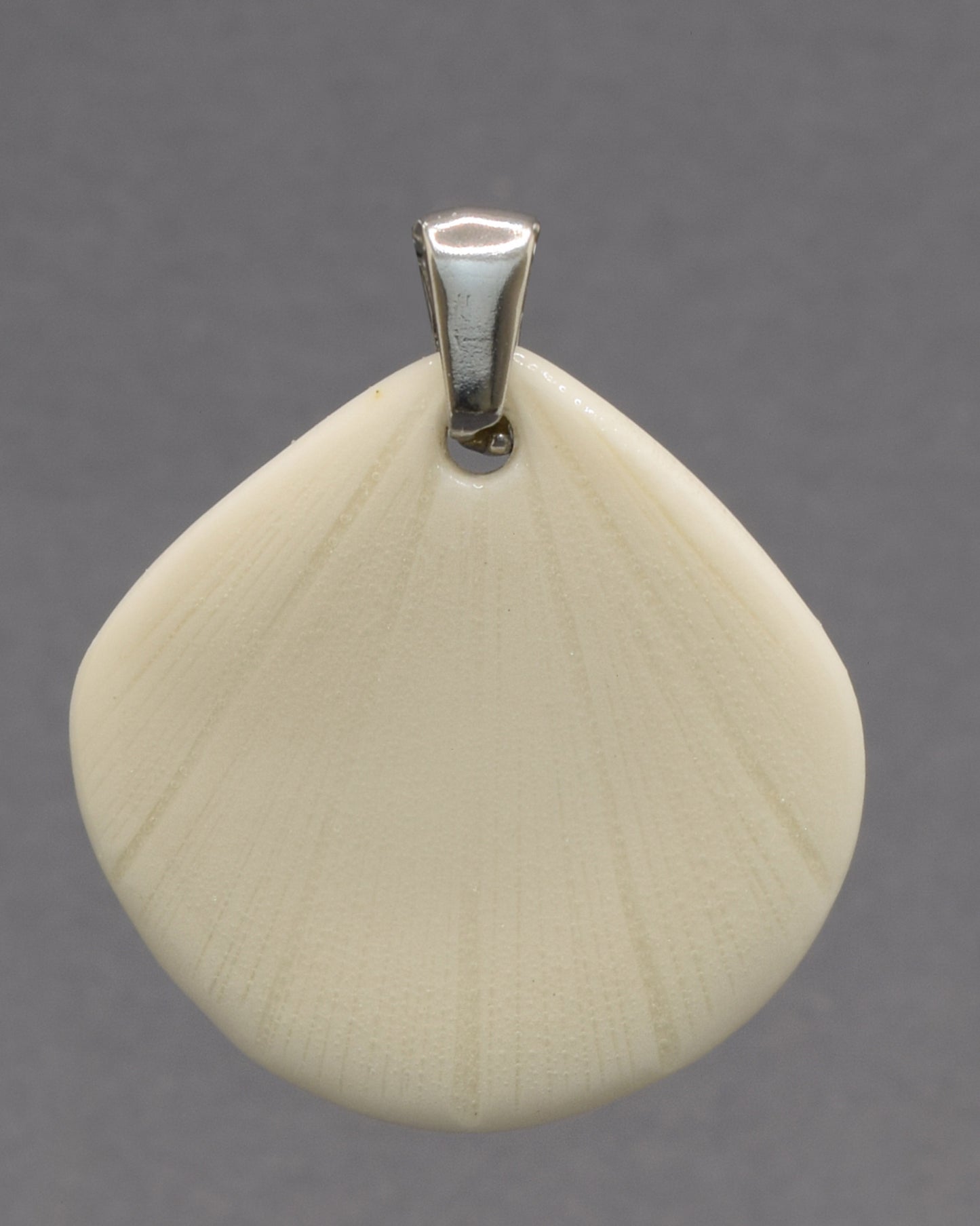 Pendente de porcelana em forma de concha, moldado e acabado à mão. Uma peça elegante que evoca a beleza do mar com delicadeza e intemporalidade.