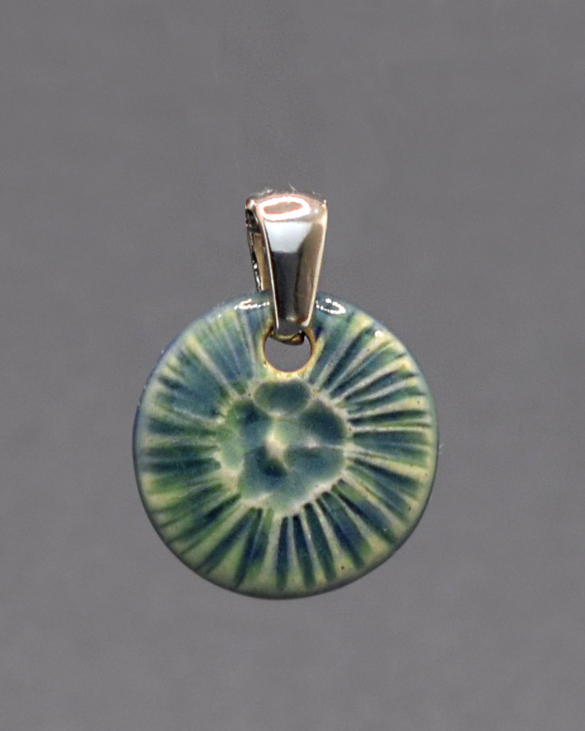 Pendente em cerâmica artesanal, inspirado numa flor do mar, em verde musgo, evocando a harmonia entre a natureza e o oceano.