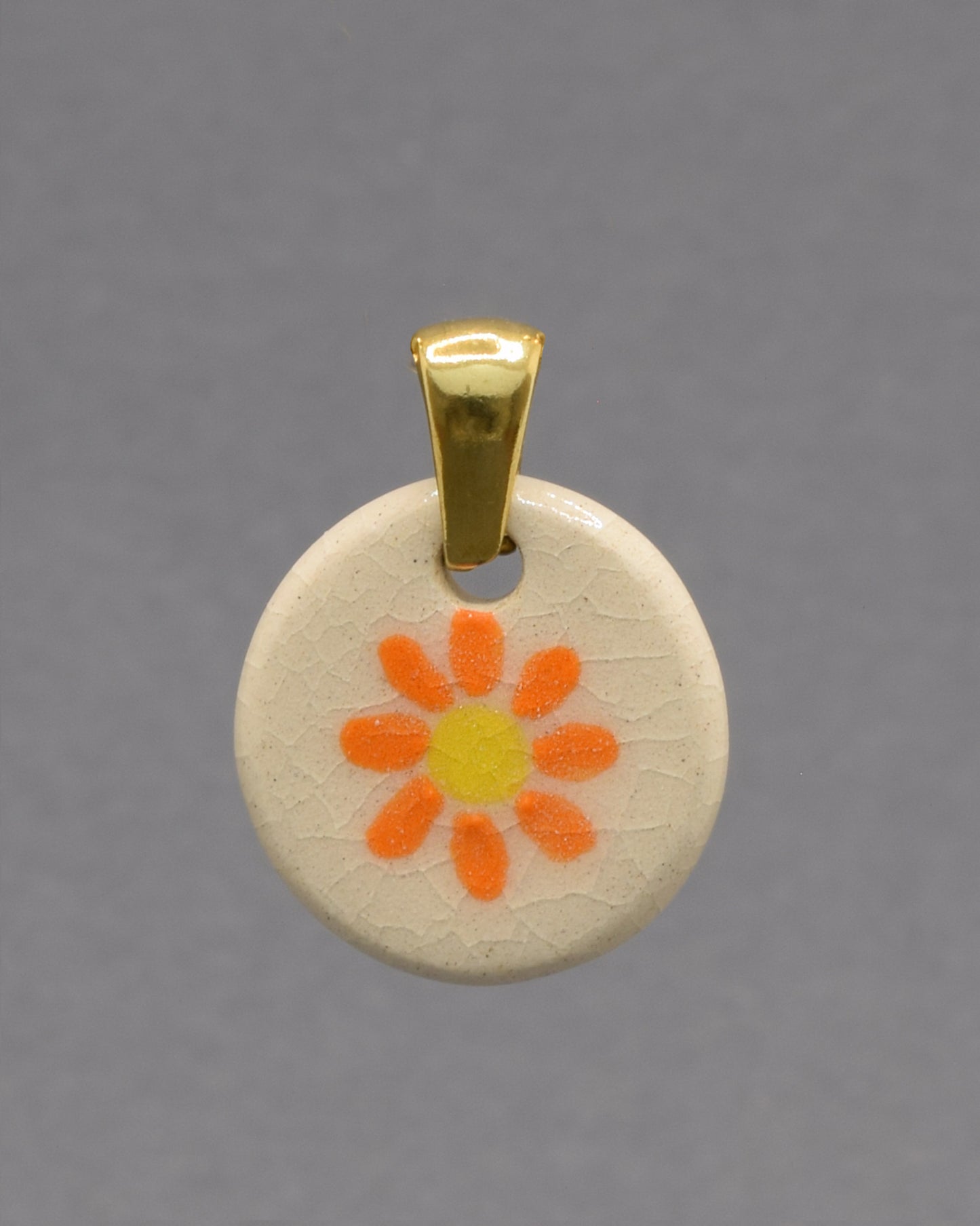 Pendente de cerâmica pintado à mão com uma delicada margarida laranja. As cores vibrantes e o acabamento artesanal tornam cada peça única e cheia de encanto.