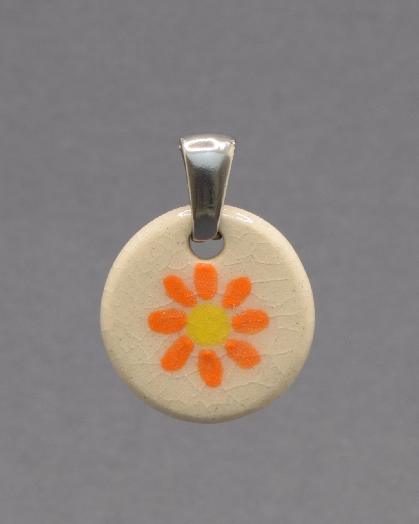 Pendente de cerâmica pintado à mão com uma delicada margarida laranja. As cores vibrantes e o acabamento artesanal tornam cada peça única e cheia de encanto.