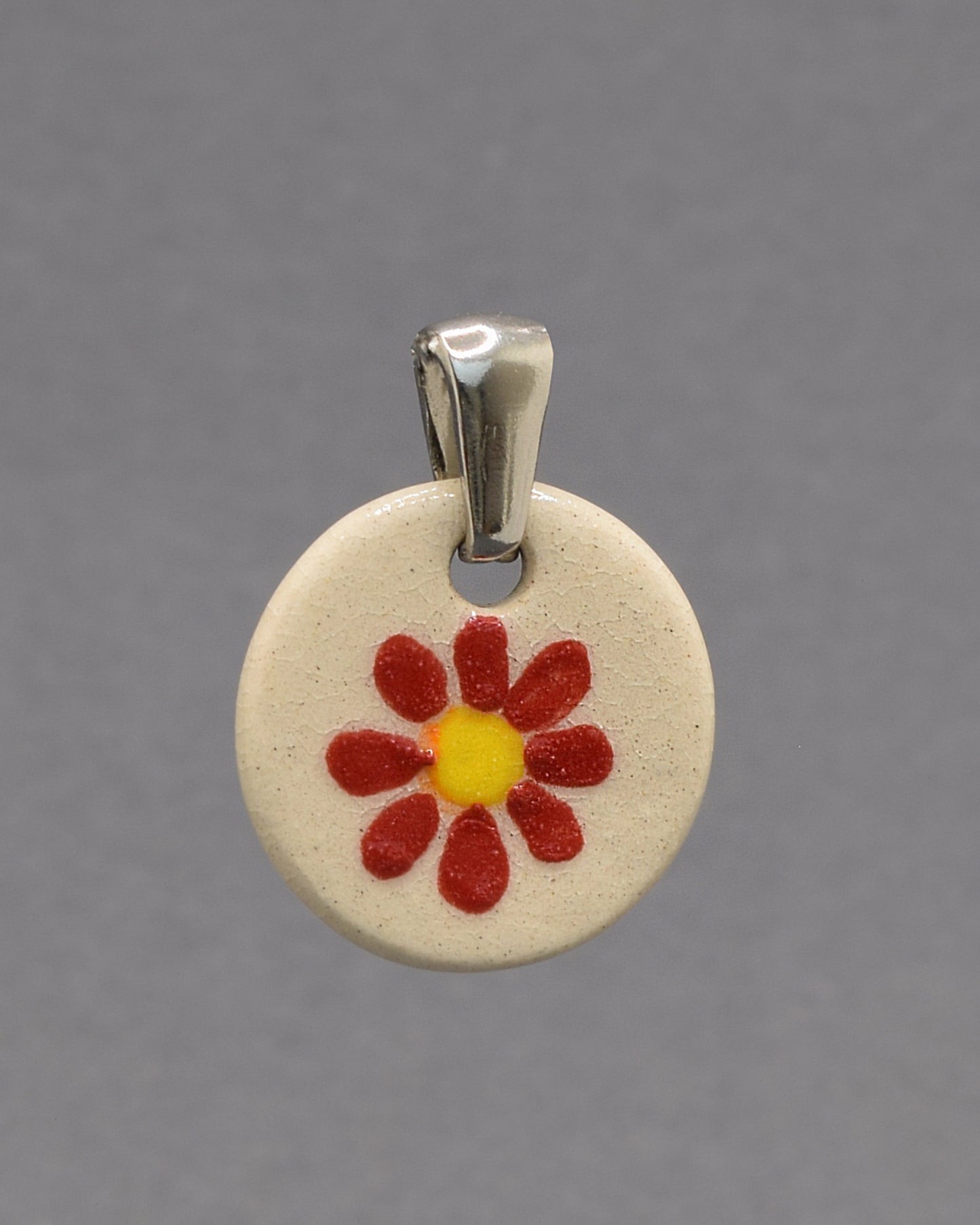 Pendente de cerâmica pintado à mão com uma delicada margarida vermelha. Uma peça artesanal que combina elegância, cor e um toque inspirado na natureza.
