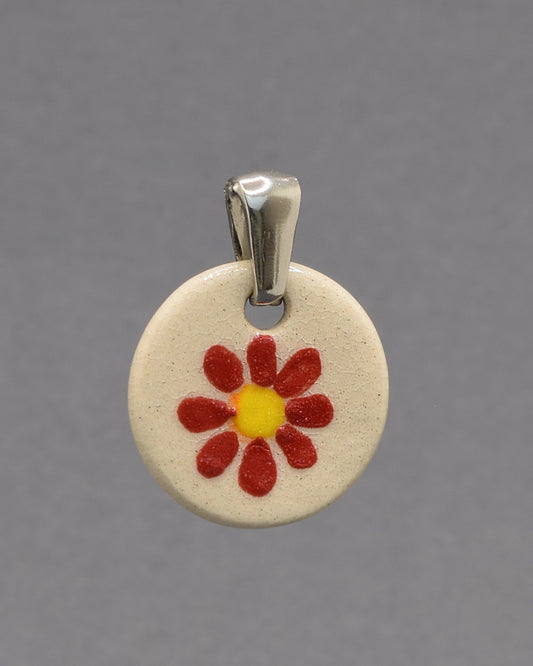 Pendente de cerâmica pintado à mão com uma delicada margarida vermelha. Uma peça artesanal que combina elegância, cor e um toque inspirado na natureza.
