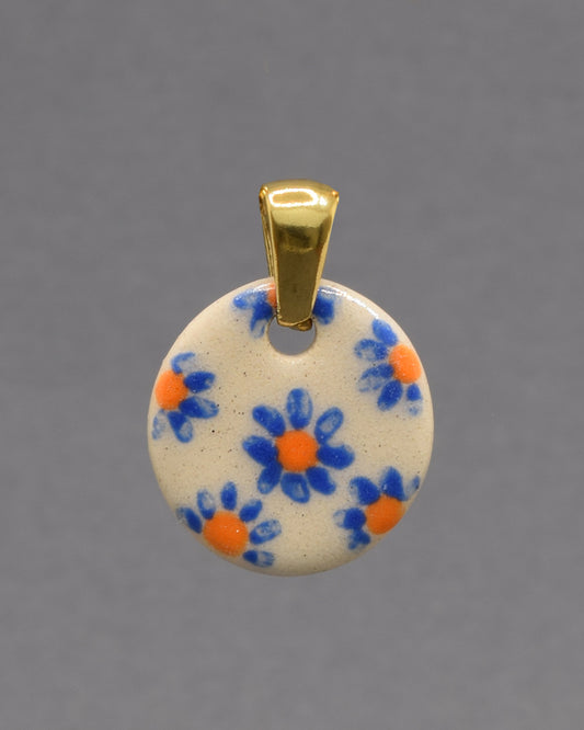 Pendente de cerâmica pintado à mão com delicadas margaridas azuis. Uma peça artesanal única, leve e elegante, perfeita para dar um toque especial ao seu look.