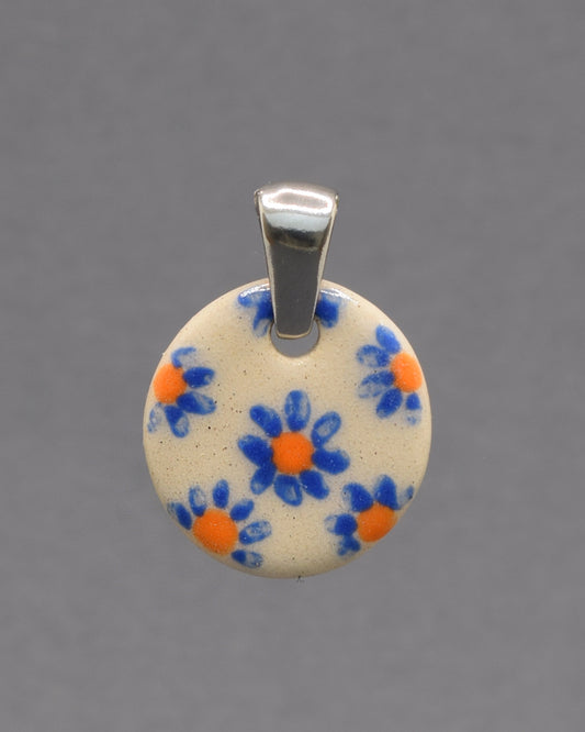 Pendente de cerâmica pintado à mão com delicadas margaridas azuis. Uma peça artesanal única, leve e elegante, perfeita para dar um toque especial ao seu look.