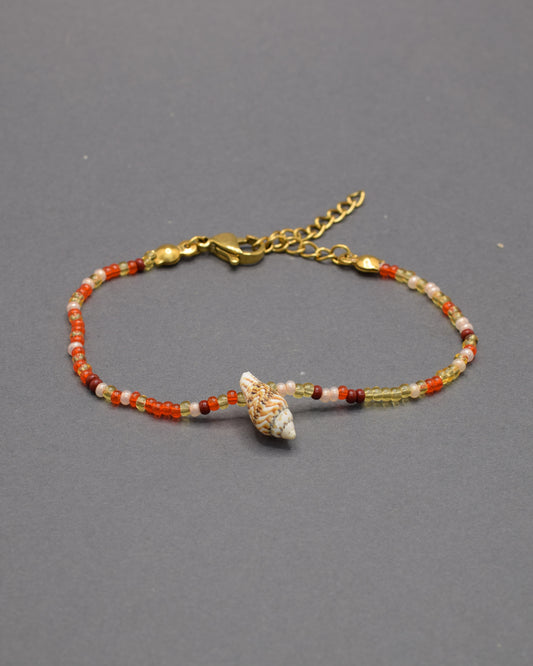 Pulseira com búzio natural e missangas de vidro em tons vermelho-alaranjado, vibrante e única, trazendo cor e personalidade ao visual.