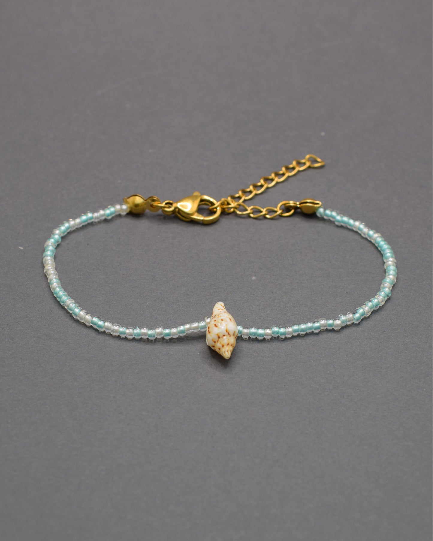 Pulseira Búzio de missangas em mix turquesa semitransparente, com brilho fresco e detalhes naturais que evocam mar e tranquilidade.