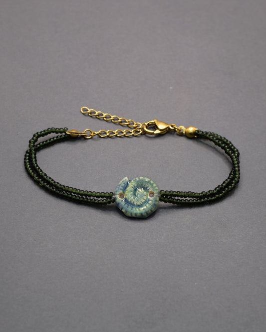 Pulseira com pendente de cerâmica caracol verde musgo, delicada e natural, perfeita para um toque original e elegante no teu look diário.