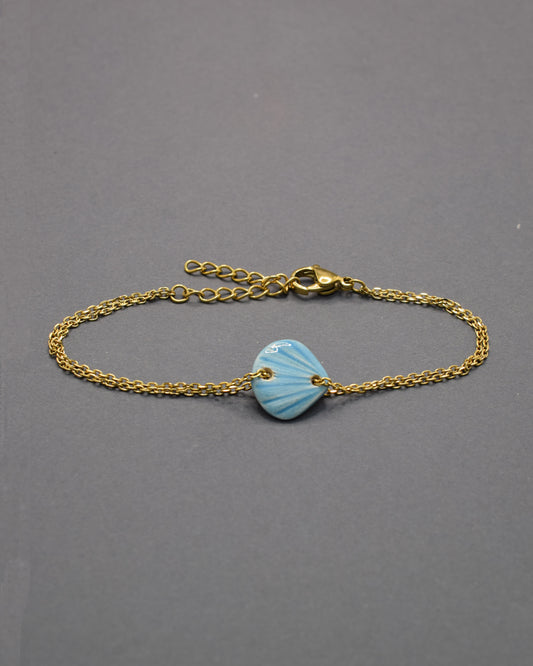 Pulseira Concha Azul Claro em cerâmica, delicada e fresca, perfeita para um toque leve e sereno que lembra o mar e os dias de verão.