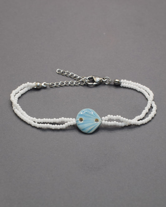 Pulseira Concha Azul Claro em cerâmica, delicada e fresca, perfeita para um toque leve e sereno que lembra o mar e os dias de verão.