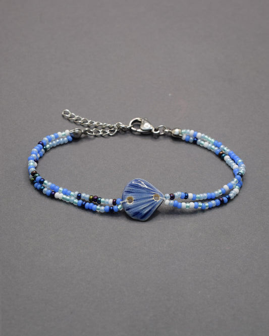 Pulseira com pendente de cerâmica em forma de concha azul escuro, elegante e sofisticada, ideal para um toque marítimo e refinado no seu look.