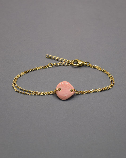 Pulseira delicada com pendente de concha rosa em cerâmica, leve e charmosa, perfeita para dar um toque praiano e elegante ao seu look.