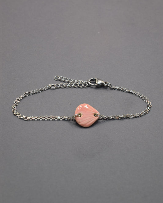 Pulseira delicada com pendente de concha rosa em cerâmica, leve e charmosa, perfeita para dar um toque praiano e elegante ao seu look.