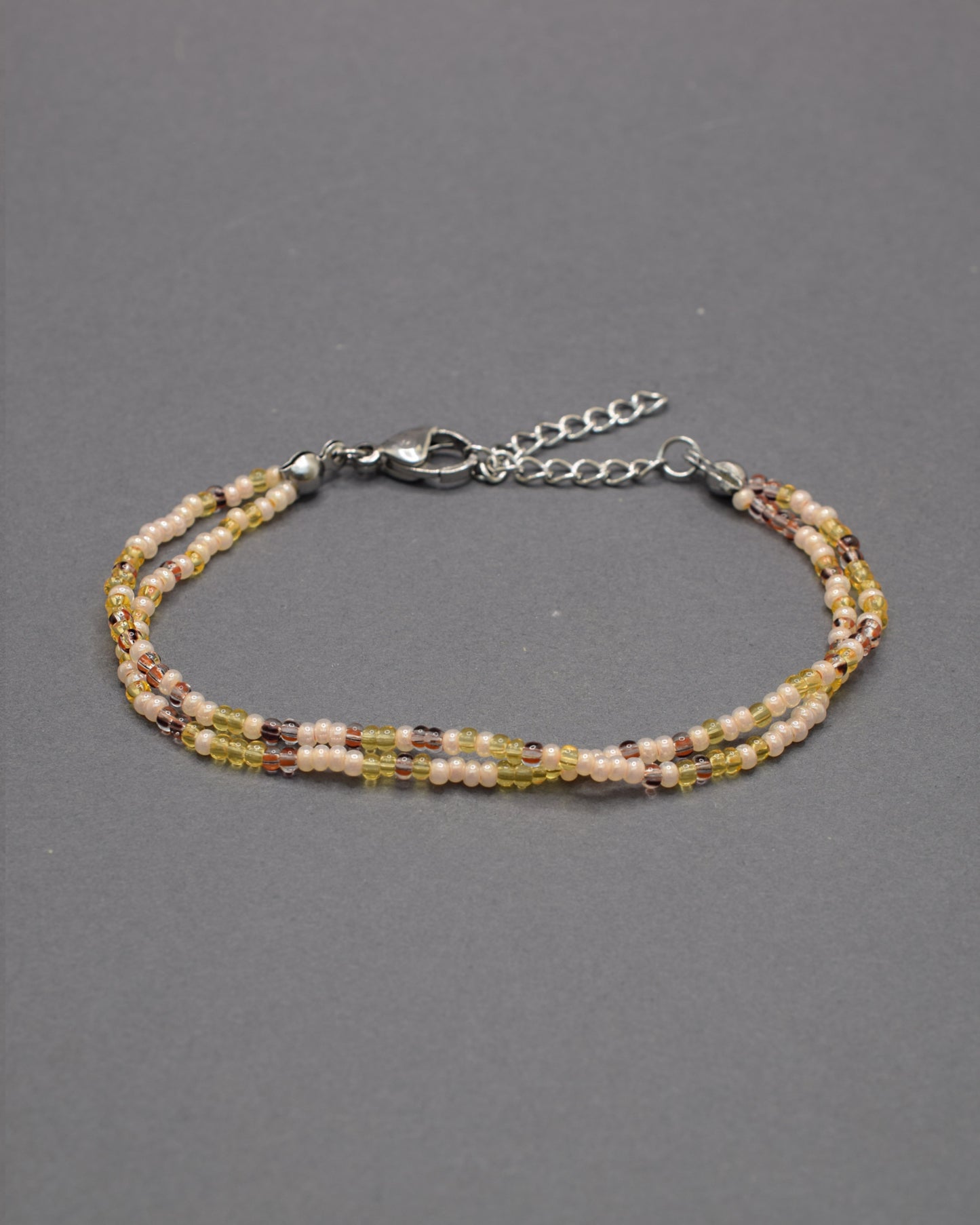 Pulseira dupla artesanal em mix dourado, combinando missangas luminosas para um look elegante e versátil, ideal para realçar qualquer estilo.