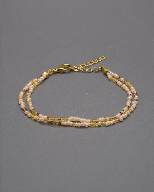 Pulseira dupla artesanal em mix dourado, combinando missangas luminosas para um look elegante e versátil, ideal para realçar qualquer estilo.
