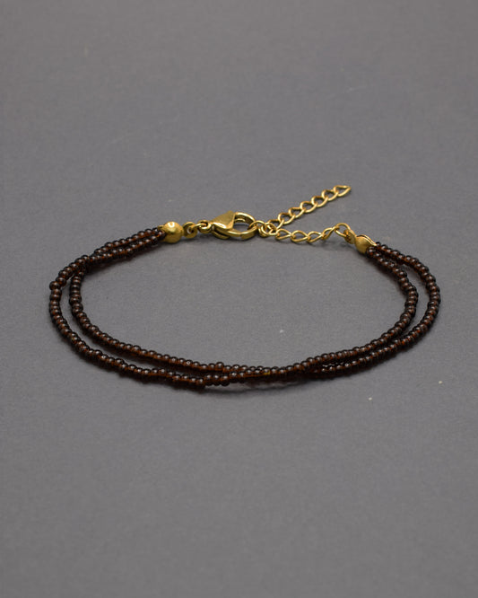 Pulseira dupla com missangas castanhas semitransparentes. Design artesanal e elegante para um toque sofisticado no seu look.