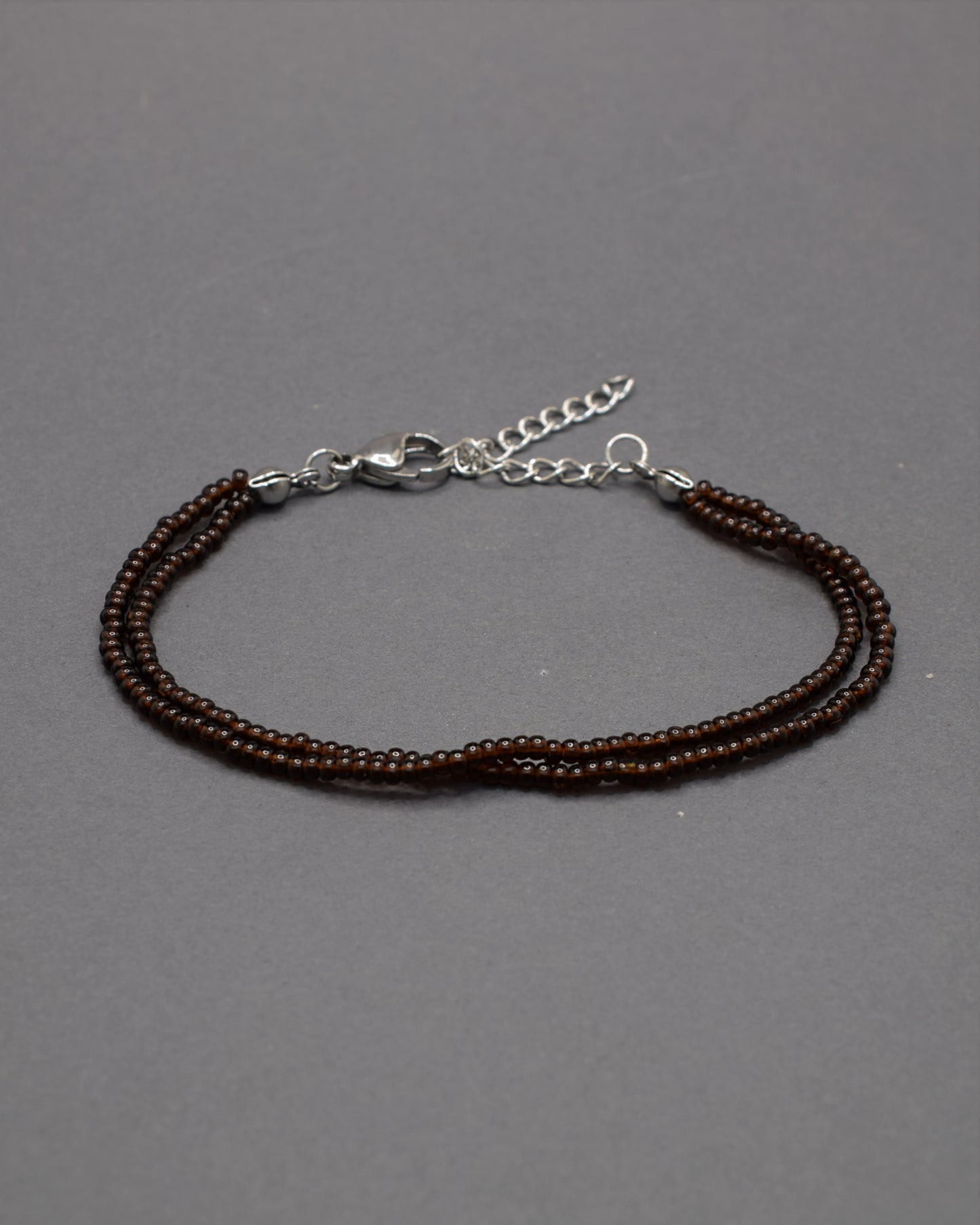 Pulseira dupla com missangas castanhas semitransparentes. Design artesanal e elegante para um toque sofisticado no seu look.