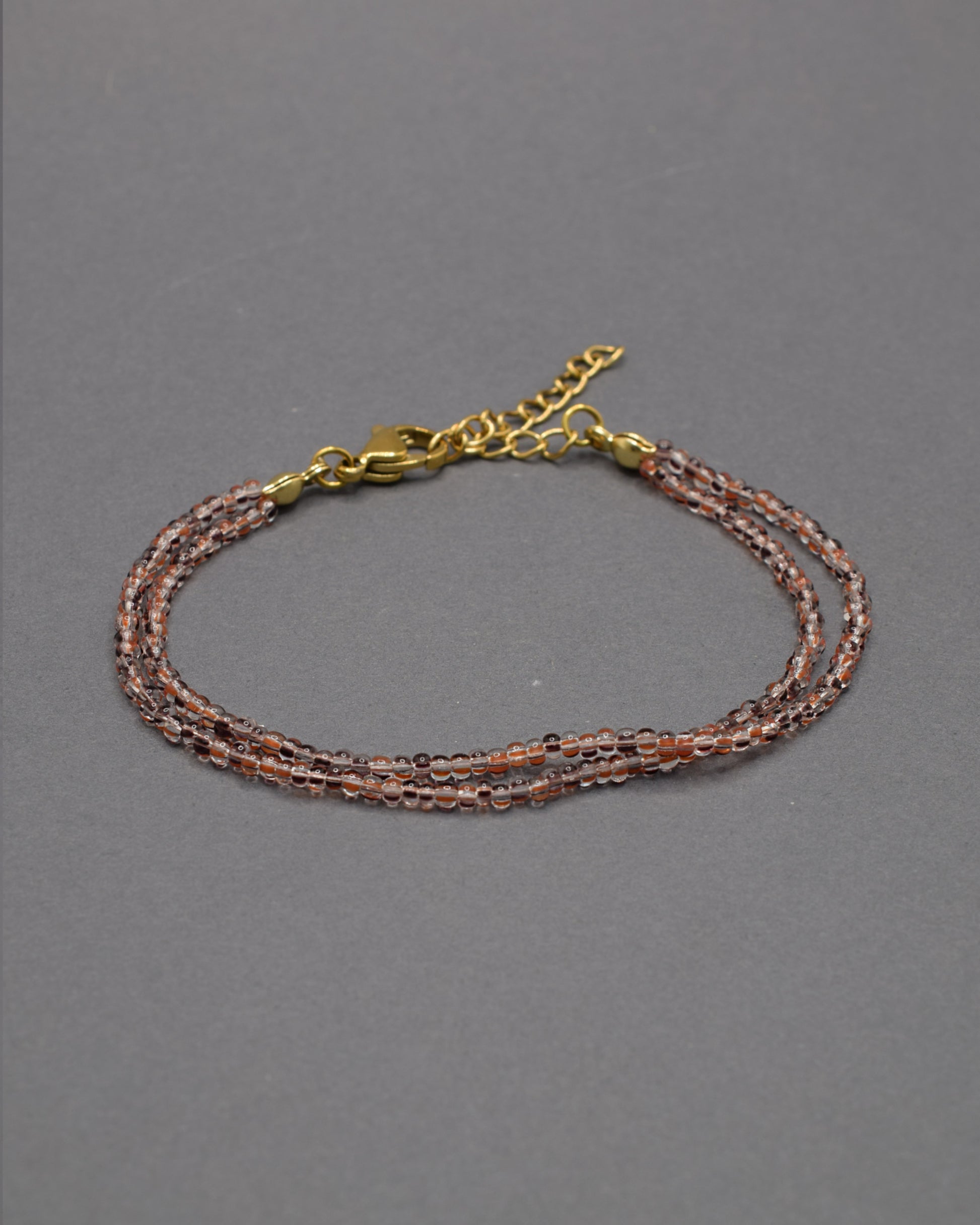 Pulseira Dupla de Missangas Listradas Castanhas, com design elegante e moderno. Perfeita para adicionar sofisticação ao seu estilo.