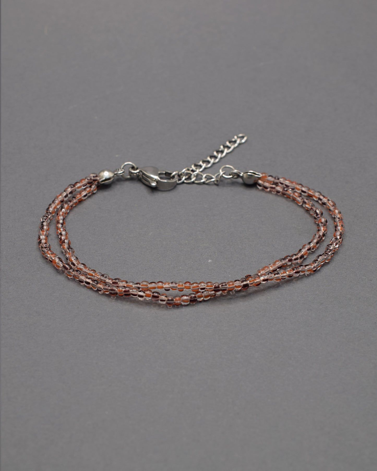 Pulseira Dupla de Missangas Listradas Castanhas, com design elegante e moderno. Perfeita para adicionar sofisticação ao seu estilo.