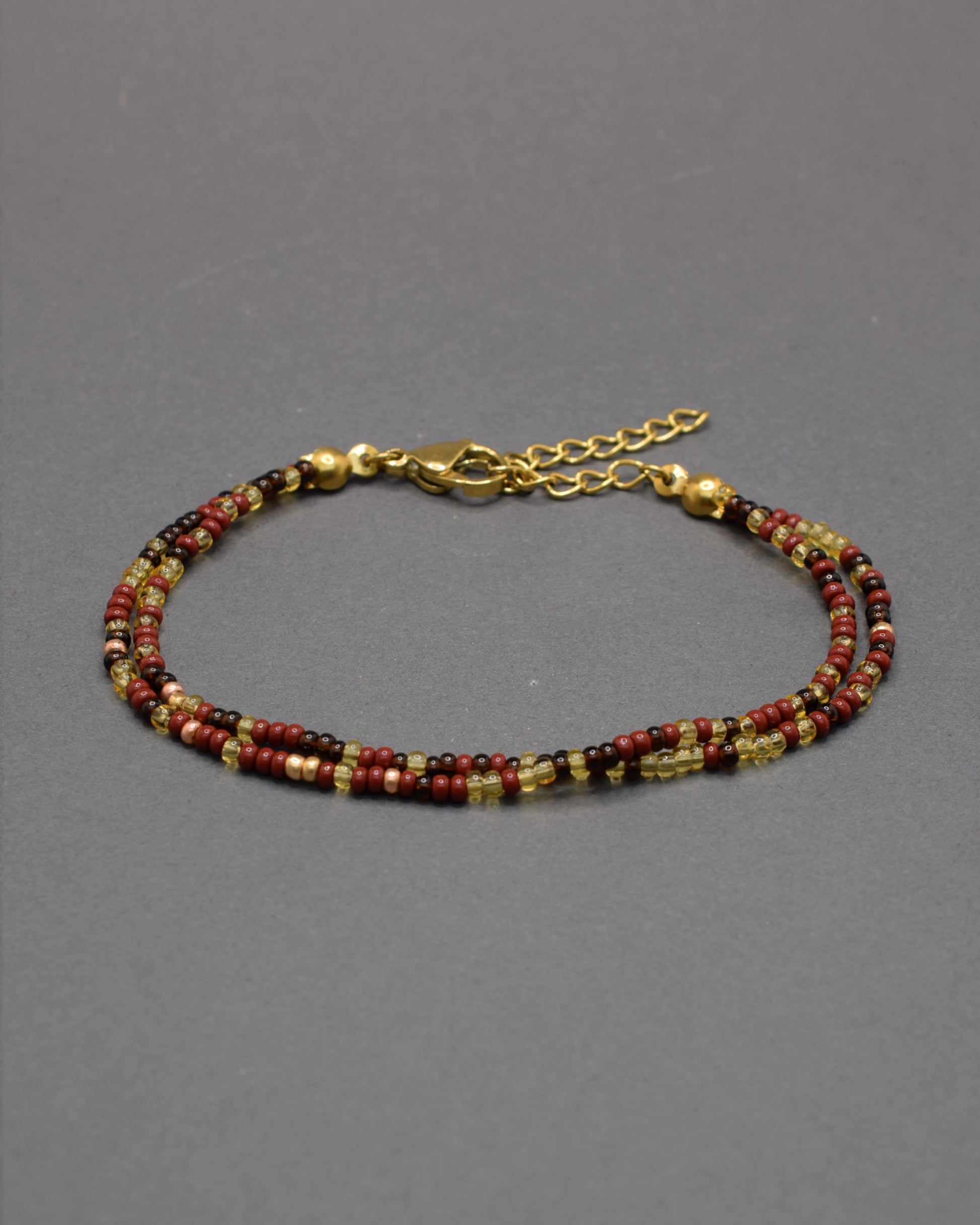 Pulseira dupla de missangas em mix bordô. Design artesanal sofisticado, ideal para um toque de cor elegante e versátil no teu look.