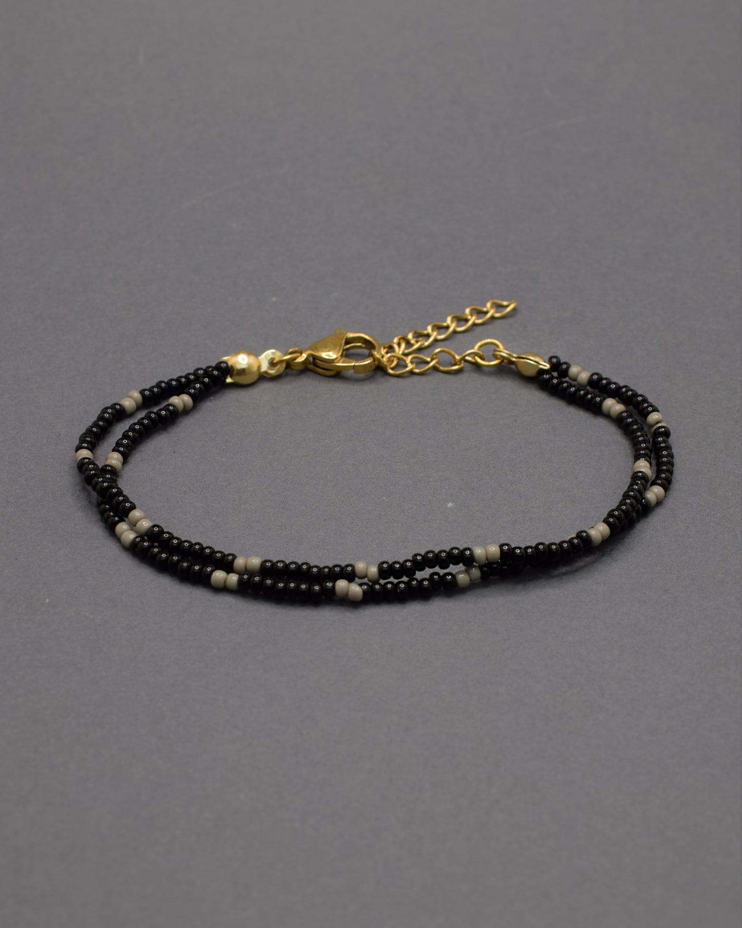 Pulseira dupla de missangas pretas com padrão cinzento. Combina força e equilíbrio, revelando um brilho subtil de elegância moderna.