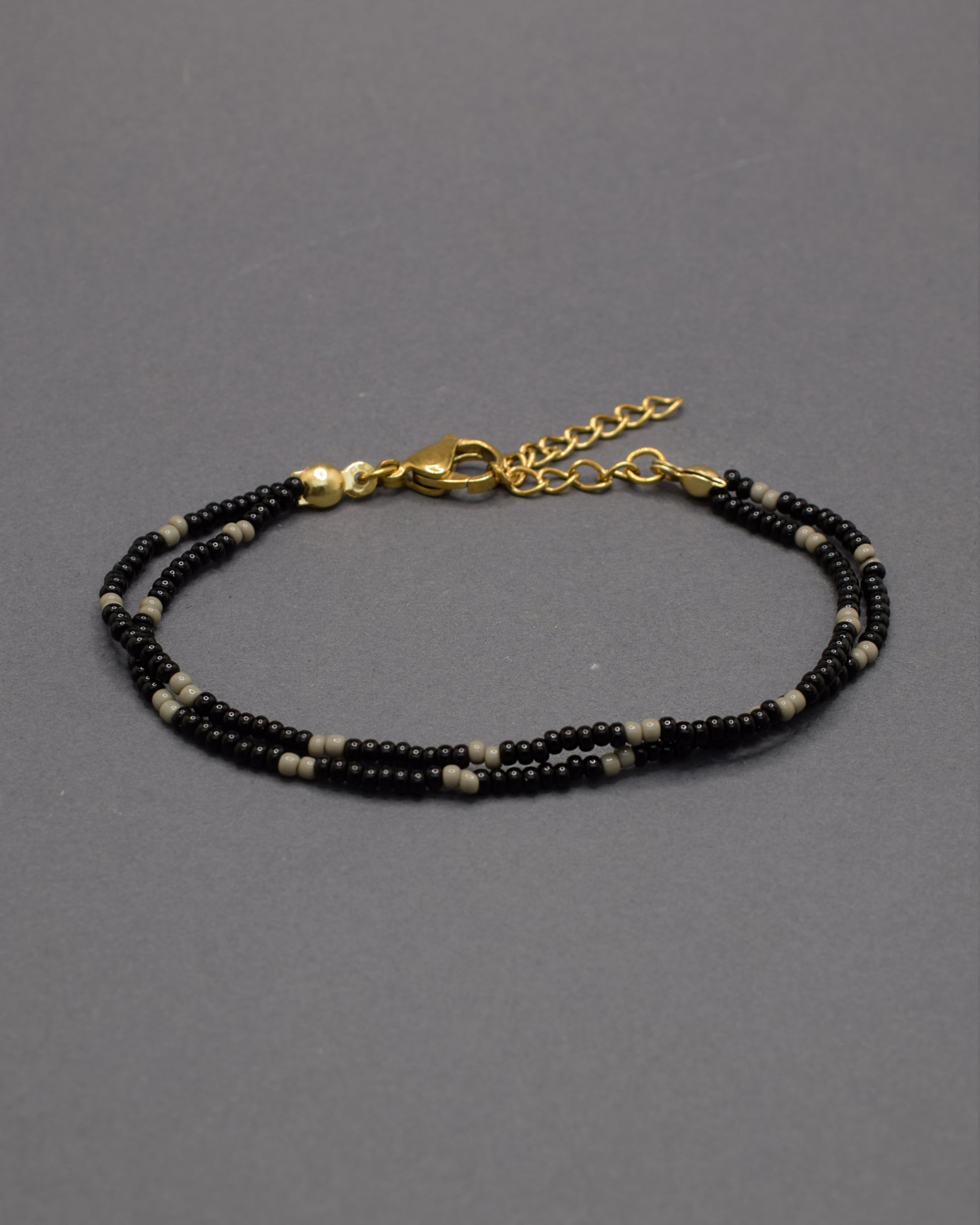 Pulseira dupla de missangas pretas com padrão cinzento. Combina força e equilíbrio, revelando um brilho subtil de elegância moderna.