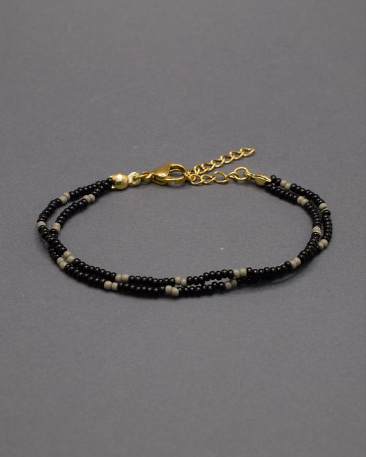 Pulseira dupla de missangas pretas com padrão cinzento. Combina força e equilíbrio, revelando um brilho subtil de elegância moderna.